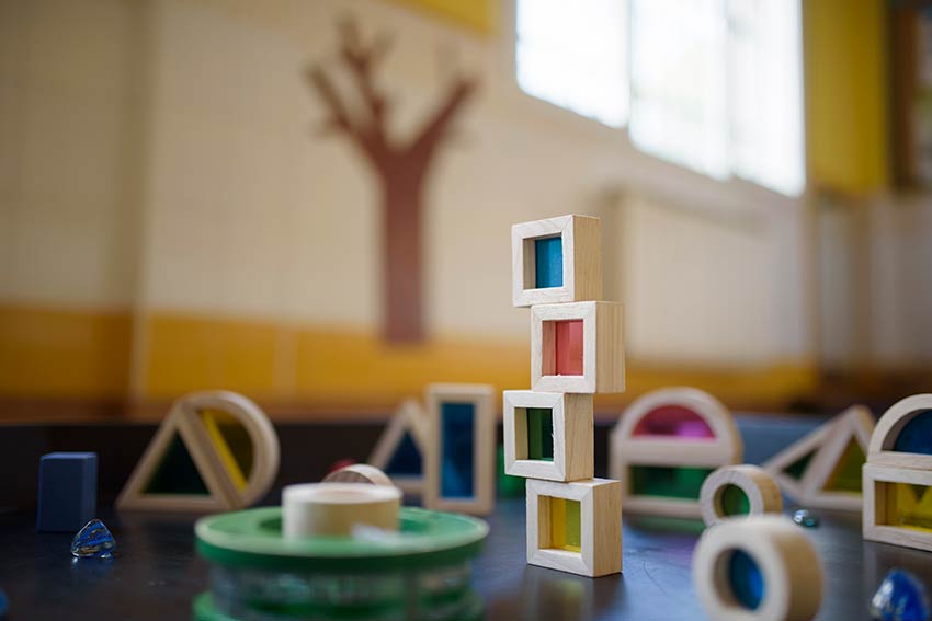Detalle de piezas puzzle de madera para jugar dispuestos en torre y dispersas.