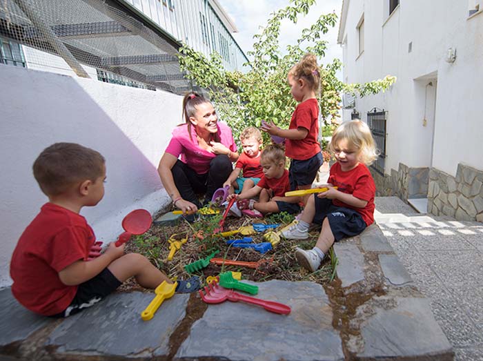 Profesora y alumnos aprendiendo a cultivar el huerto escolar infantil en Monachil